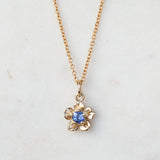 gold forget me not flower necklace with a sapphire